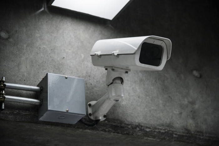 Kamera monitoringu na betonowej ścianie, pod lampom, obok metalowej puszki na elektronikę