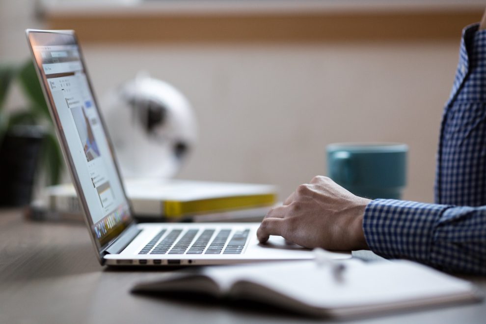 Mężczyzna w koszuli w niebiesko białą kratkę pracujący na laptopie